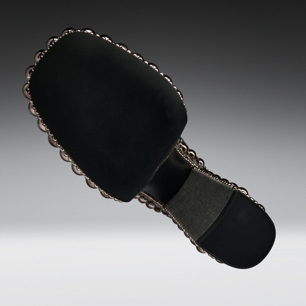 A black fabric-covered shoe sole with a decorative scalloped metallic edge and a gray footbed, shown on a gradient gray background.