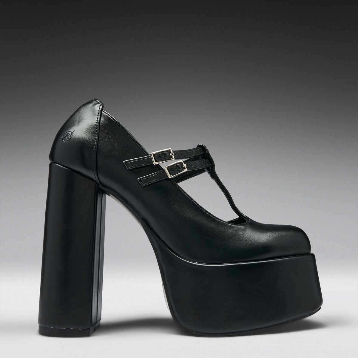 A single black leather platform Mary Jane shoe with a chunky block heel and double buckle straps, shown from a side profile on a dark gray to light gray gradient background.