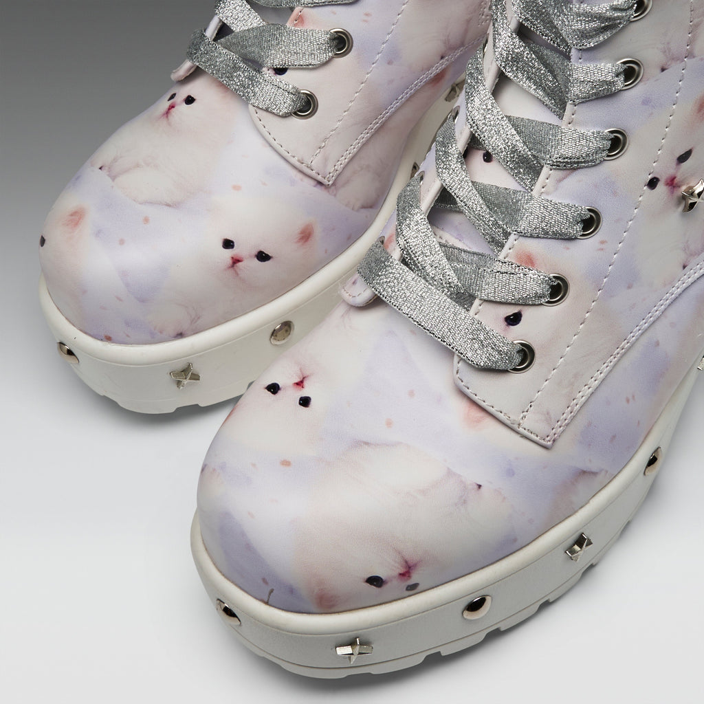 A pair of platform ankle boots featuring a pastel lavender and white cat print, silver glitter laces, and silver metal studs on the white soles.