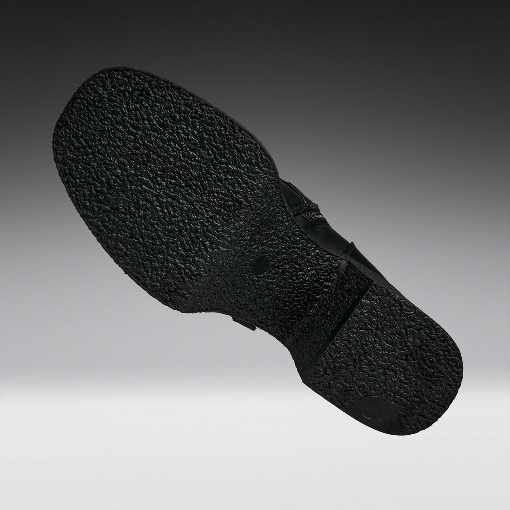 A close-up of a black textured shoe sole, shown floating against a gradient gray background.