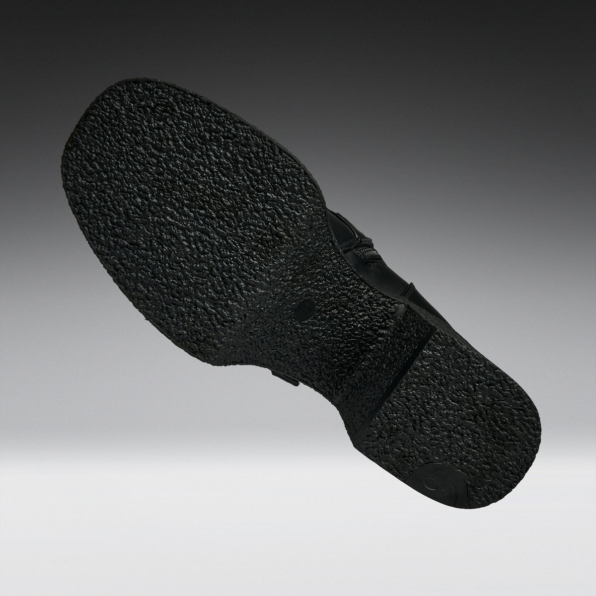 A close-up of a black textured shoe sole, shown floating against a gradient gray background.