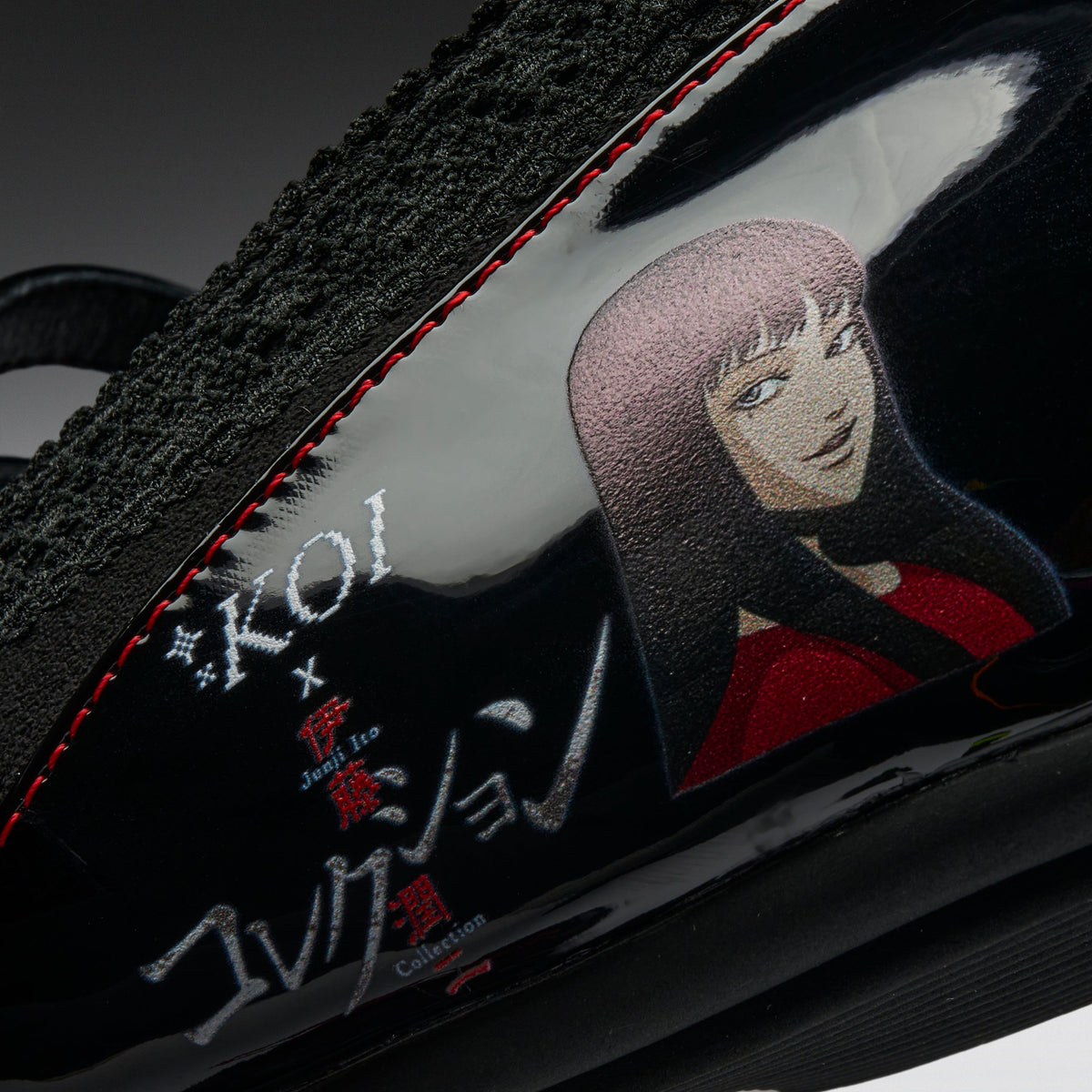Close-up of a black sneaker featuring a glossy side panel with red stitching, a stylized anime character illustration, and white and red text reading 'KOI x Just for Coaster Collection'.