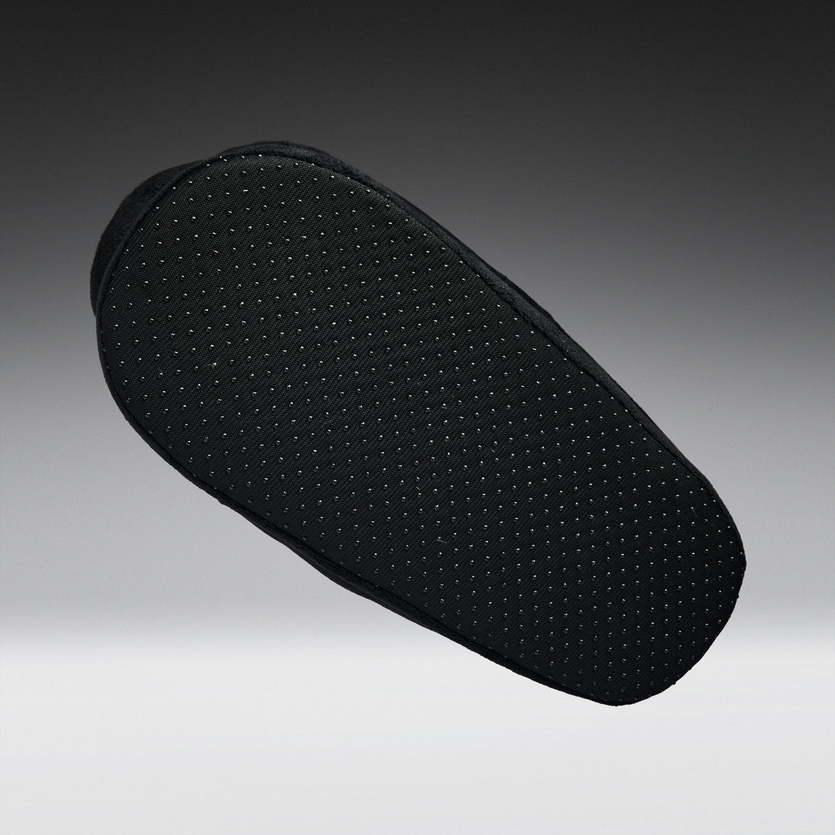 A black textured shoe cushion with a perforated grip pattern, shown floating against a dark gray gradient background.