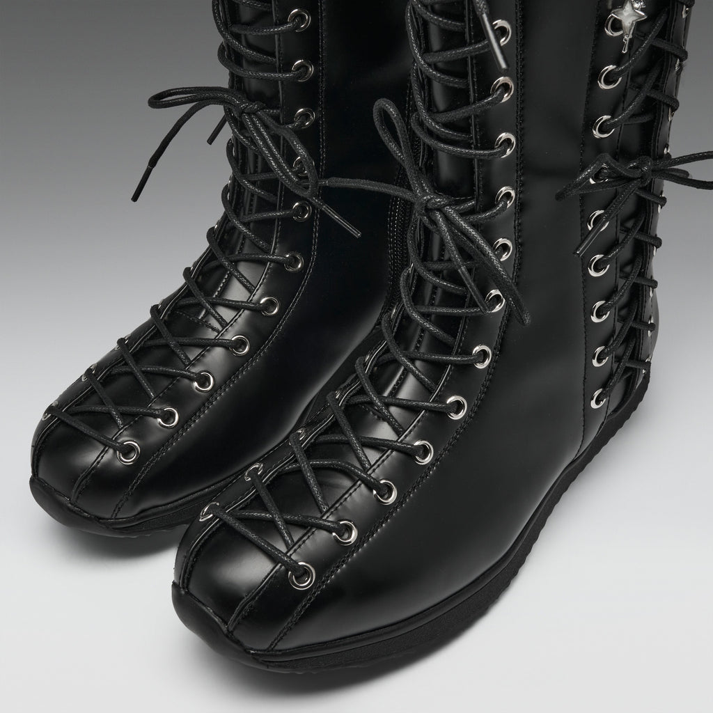 A pair of black leather lace-up boots with silver metal eyelets, shown on a neutral gray background.