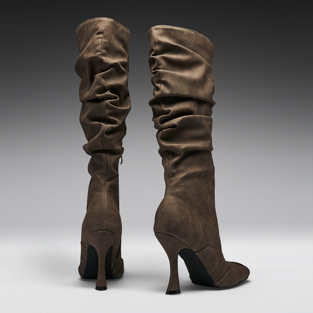 A pair of tall, slouchy knee-high boots in a dark brown suede-like material, shown from the back against a dark-to-light gray gradient studio background.