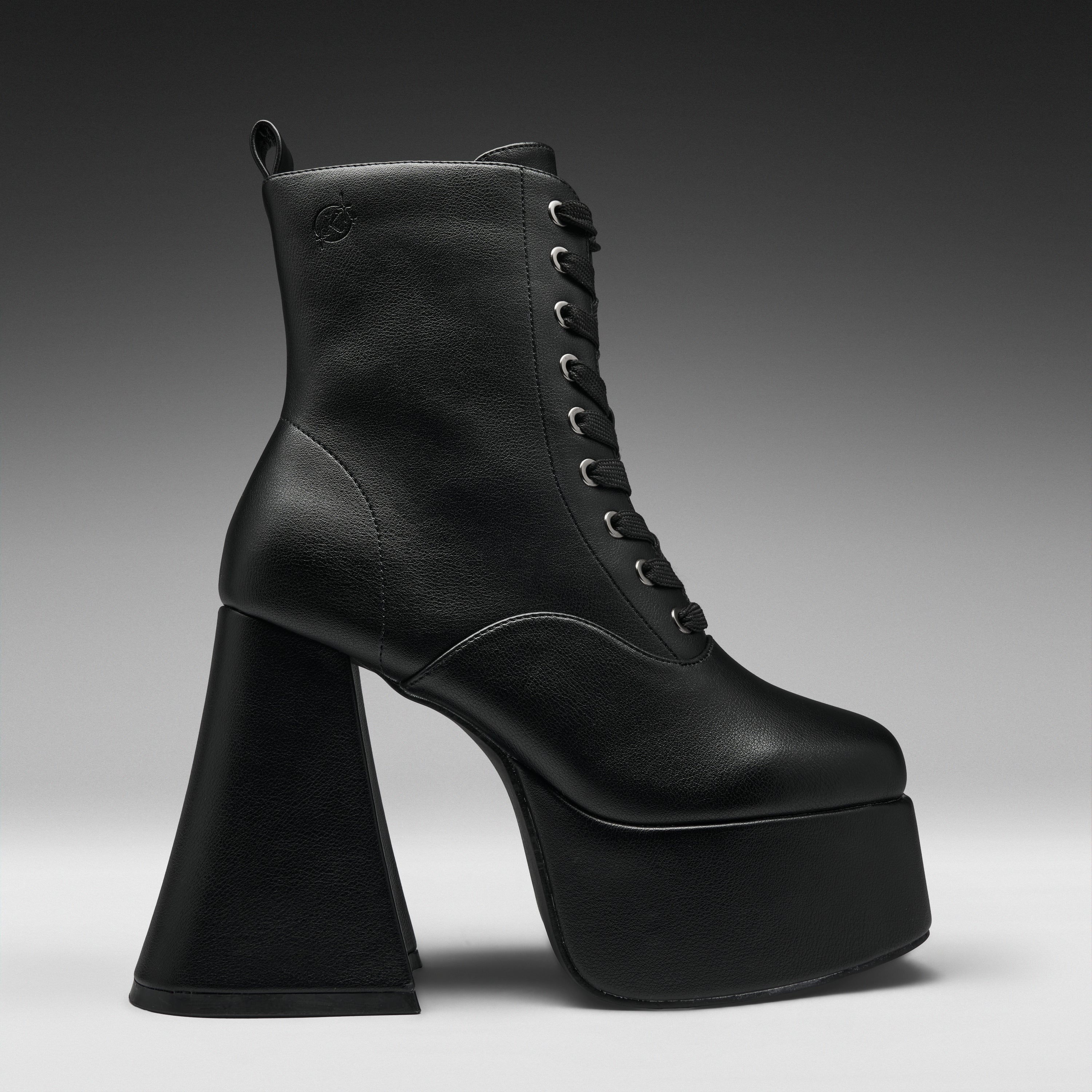 A single black leather lace-up ankle boot with a dramatic high block heel and platform sole, shown in profile against a dark gray gradient studio background.