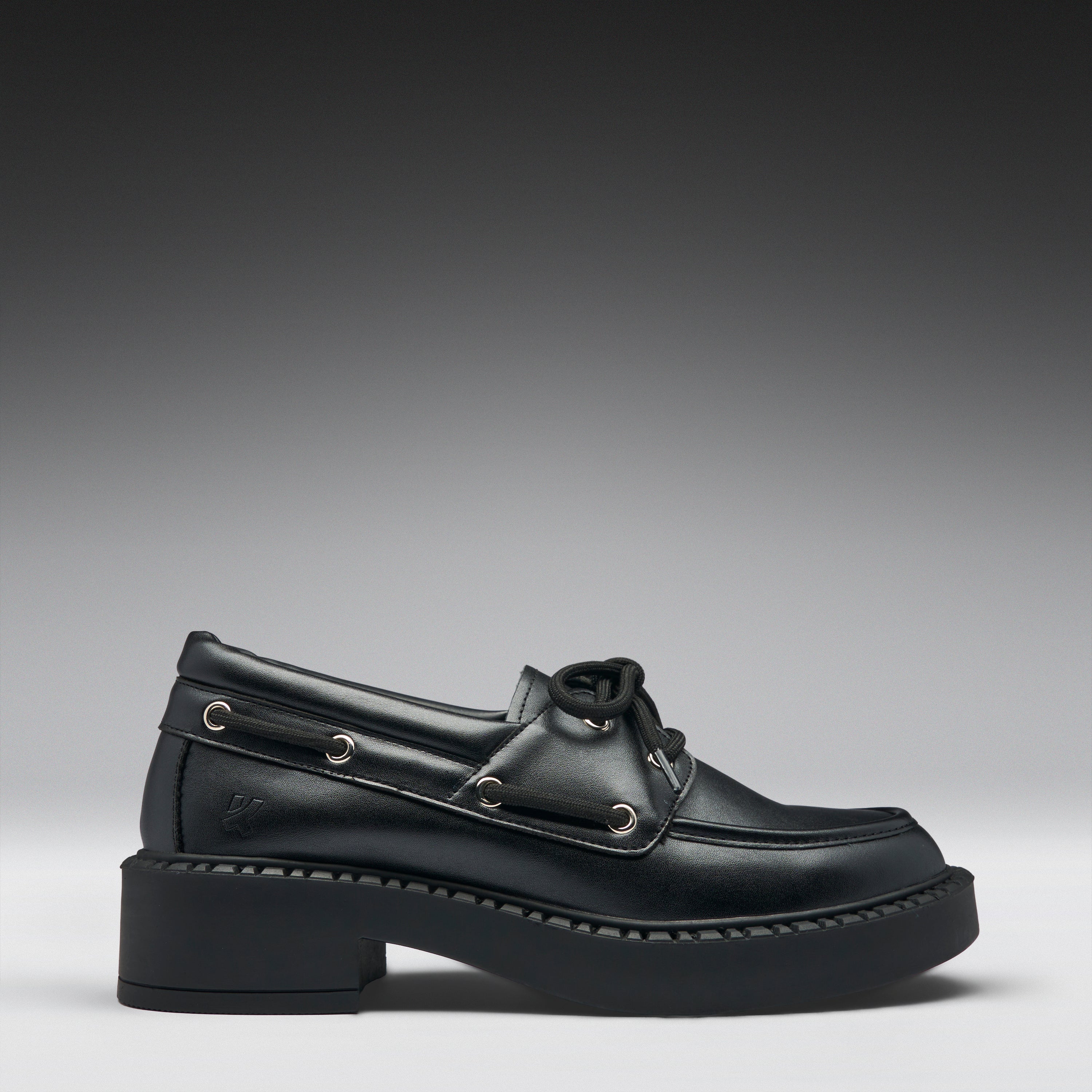Black leather boat shoe on a gradient gray background