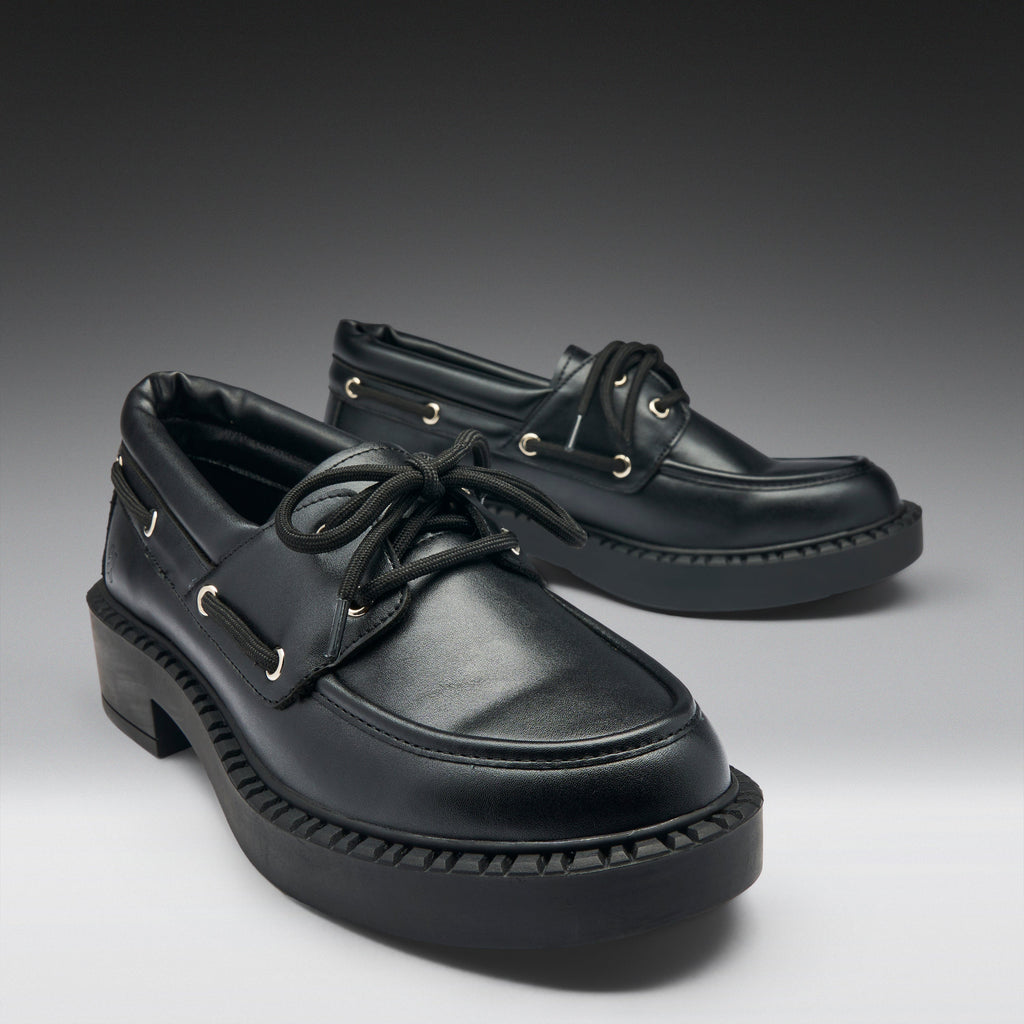 Pair of black leather shoes on a gradient gray background