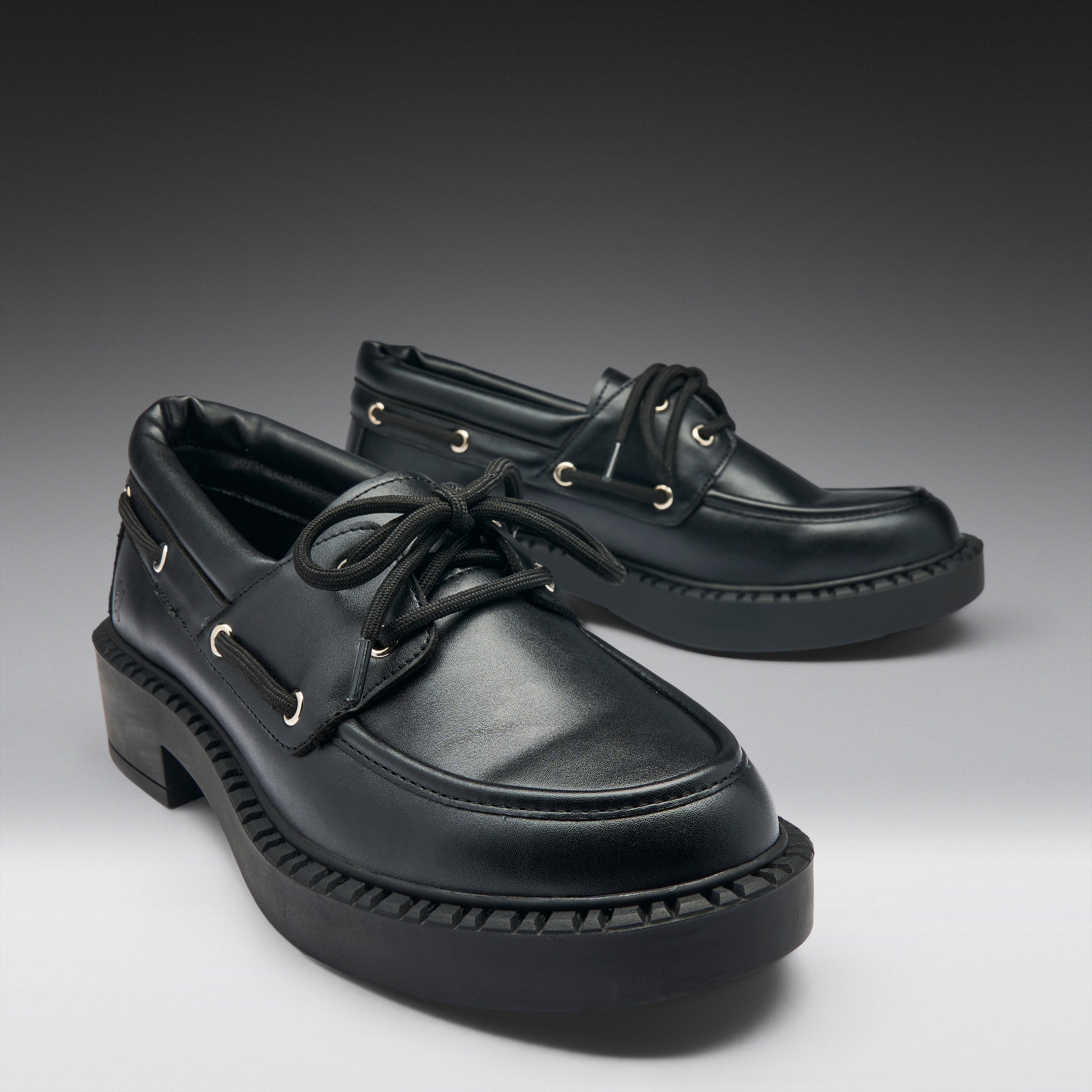 Pair of black leather shoes on a gradient gray background