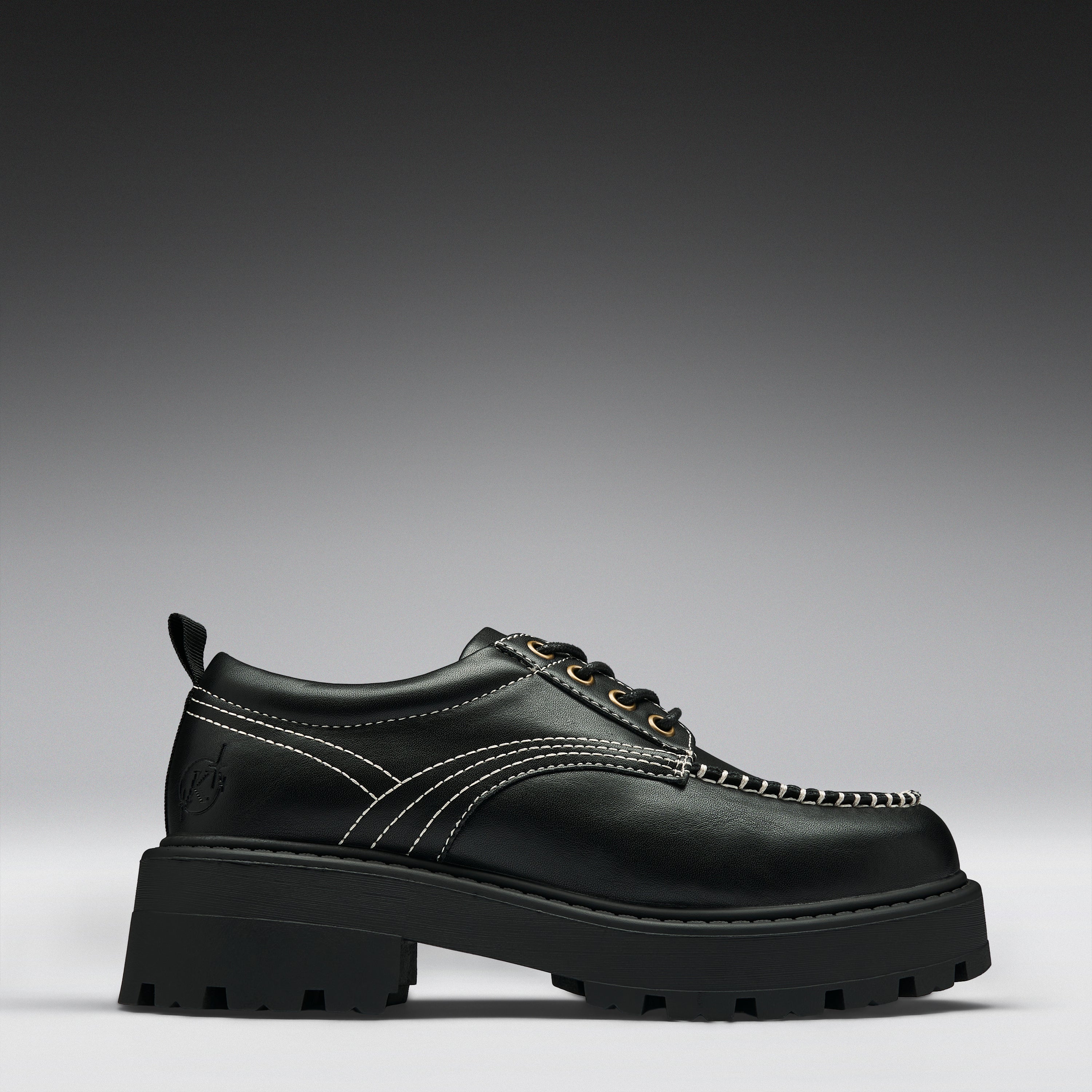 A black leather lace-up boot with a chunky lug sole, contrast white stitching, and gold-tone eyelets, shown in a side profile on a gray gradient background.