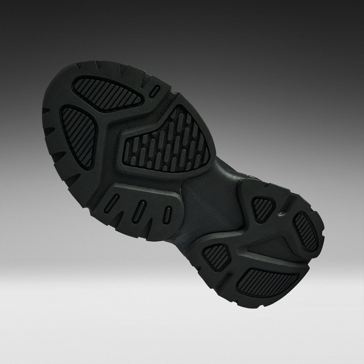 A close-up of a black athletic shoe's textured outsole, shown from a side angle against a dark-to-light gray gradient background.