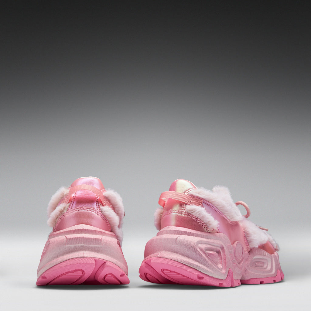 A pair of pink chunky sneakers shown from the back, featuring fuzzy white faux-fur trim and translucent pink soles, set against a dark-to-light gray gradient studio background.