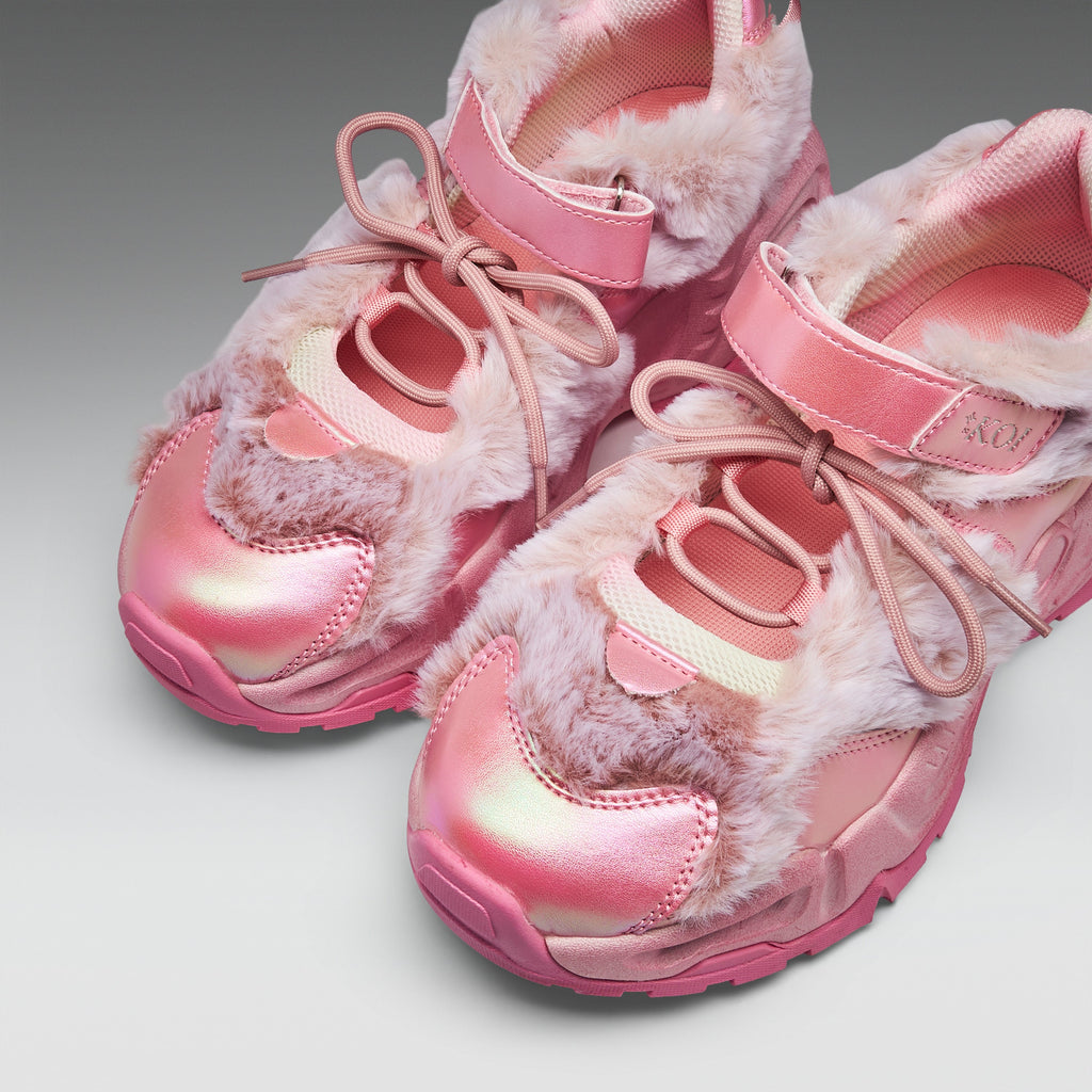 A pair of pink chunky sneakers with fluffy faux-fur trim, metallic pink toe caps, and matching pink laces, photographed on a clean light gray studio background.