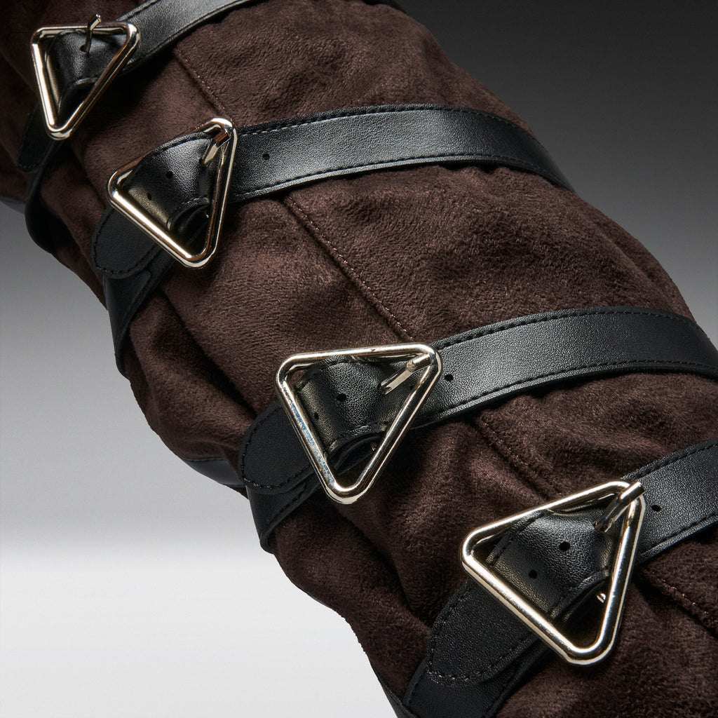 Close-up of a dark brown suede or faux-suede garment with multiple black leather straps and large triangular silver metal buckles.